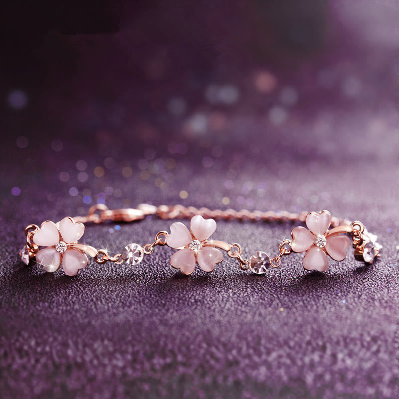 Crafted with rose gold-plated chain featuring three cherry blossom pink cat's eye clover flowers, each accented with sparkling crystal centers and star-shaped links, this bracelet exudes soft romance and symbolizes luck, hope, and love—perfect for gifting or personal wear.