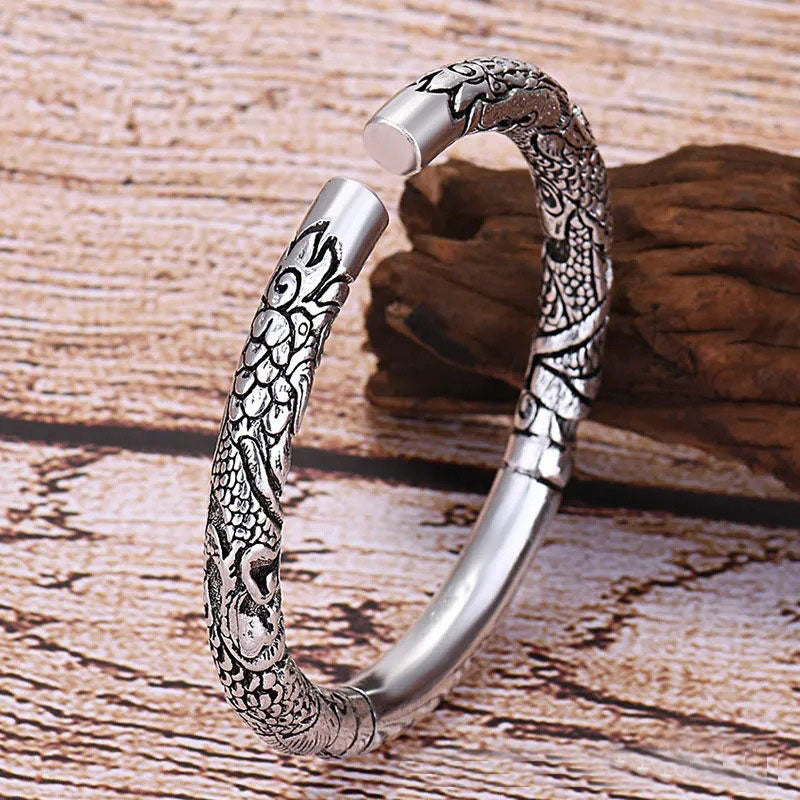 Silver bracelet with intricate designs on a wooden surface