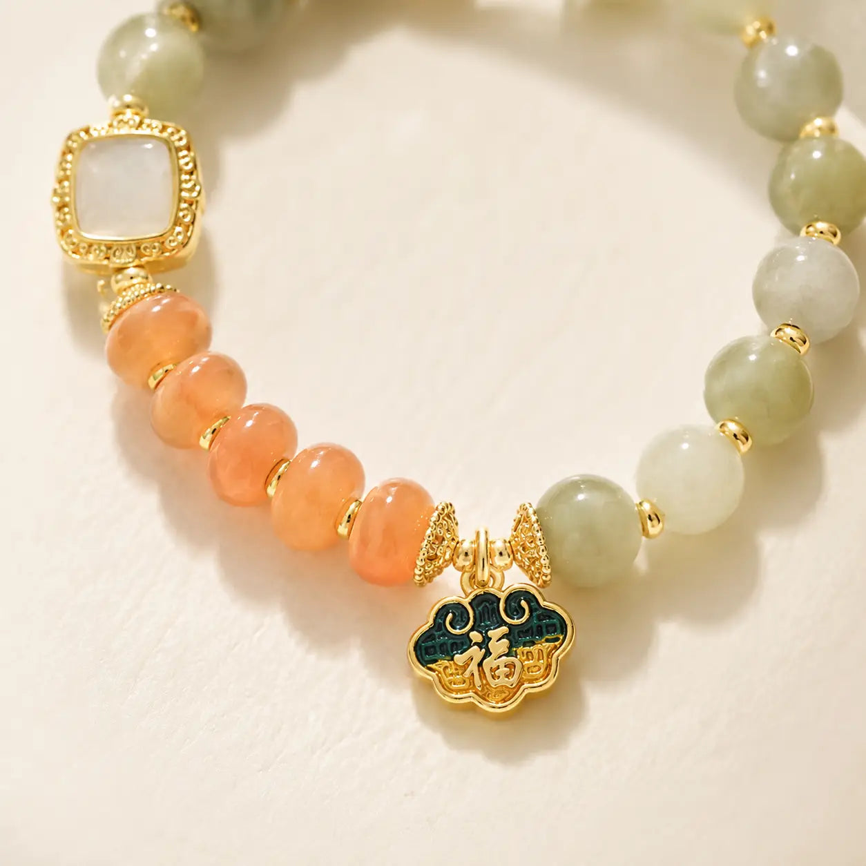 Close-up of Golden Silk Jade bracelet with orange beads and gold charm