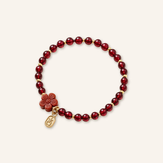 Living Vitality Garnet Cinnabar Flower Bracelet featuring deep garnet beads, a carved cinnabar flower charm, and a small gold accent pendant in a clean product image.
