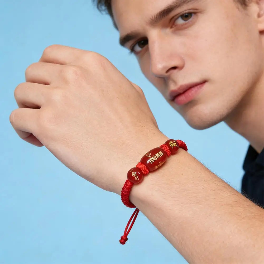 Person wearing a red bracelet on a blue background