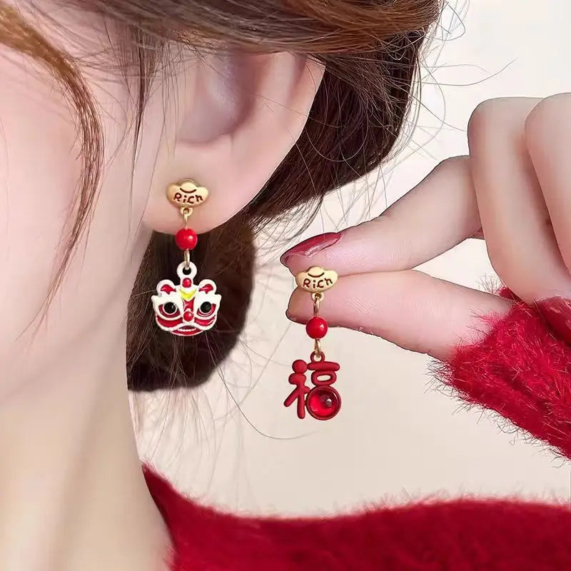 Earrings with red beads and gold accents worn by a person against a neutral background