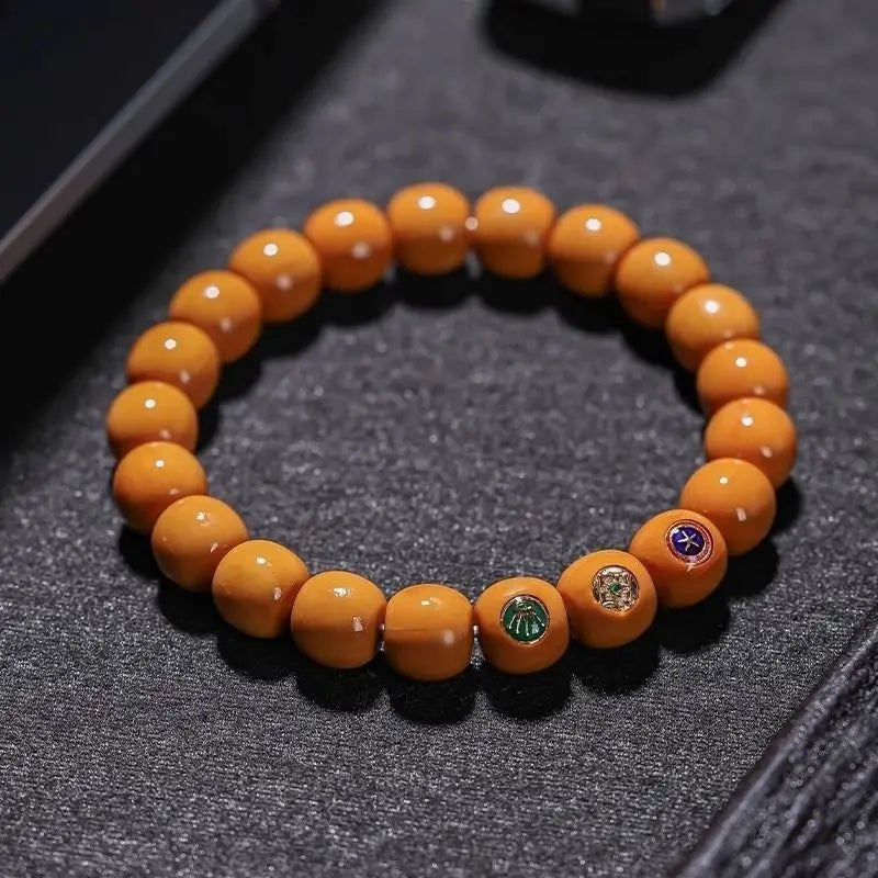 Orange beaded bracelet with colorful stones on a dark textured surface