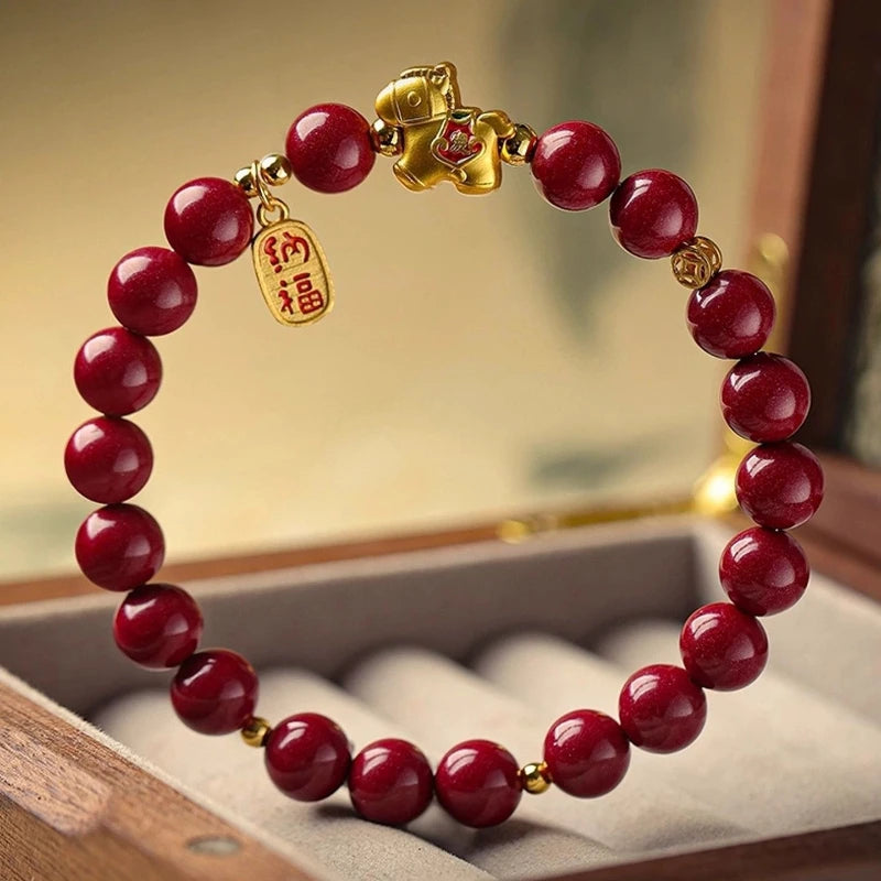Red beaded bracelet with a gold charm on a wooden surface
