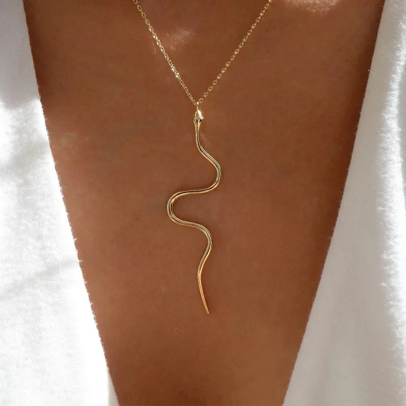 Gold snake-shaped necklace on a person's neck against a white background