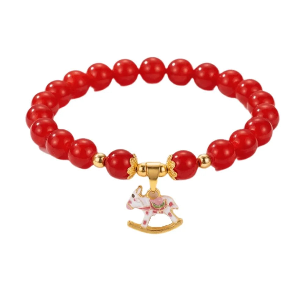 Red beaded bracelet with a gold clasp and pink rocking horse charm on a white background
