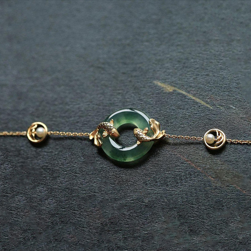 Delicate bracelet with green stone and gold accents on a dark background