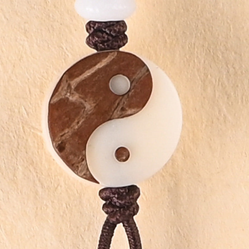 Decorative wall light fixture with yin yang design on a beige wall.