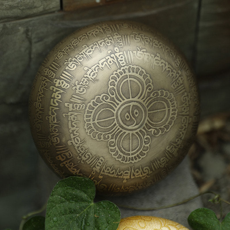Decorative stone with engraved symbols and text, surrounded by greenery.