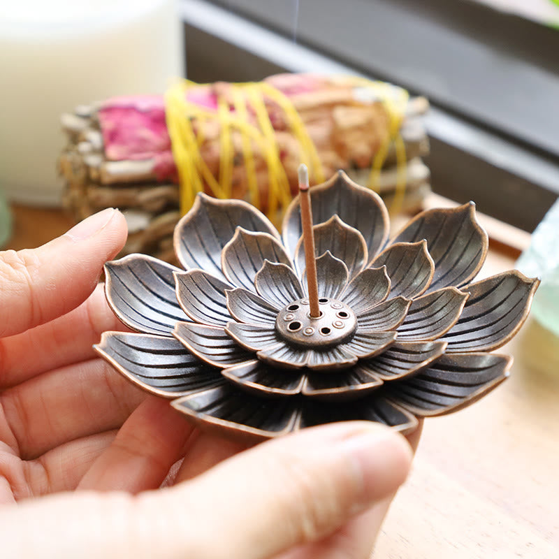Lotus-shaped incense burner held by a hand with blurred background