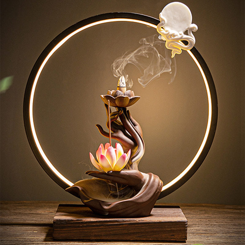 Decorative incense burner with lotus design and circular light fixture on a wooden base.