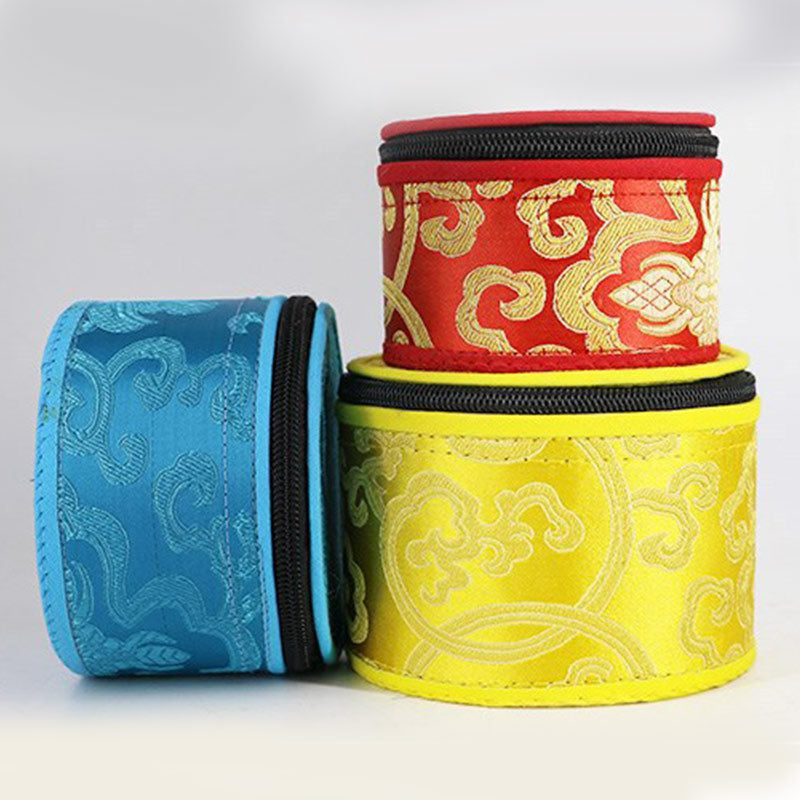Three cylindrical fabric containers with intricate patterns in red, blue, and yellow on a light gray background.