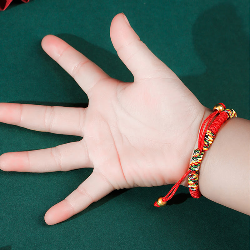 Hand wearing a colorful bracelet on a green background