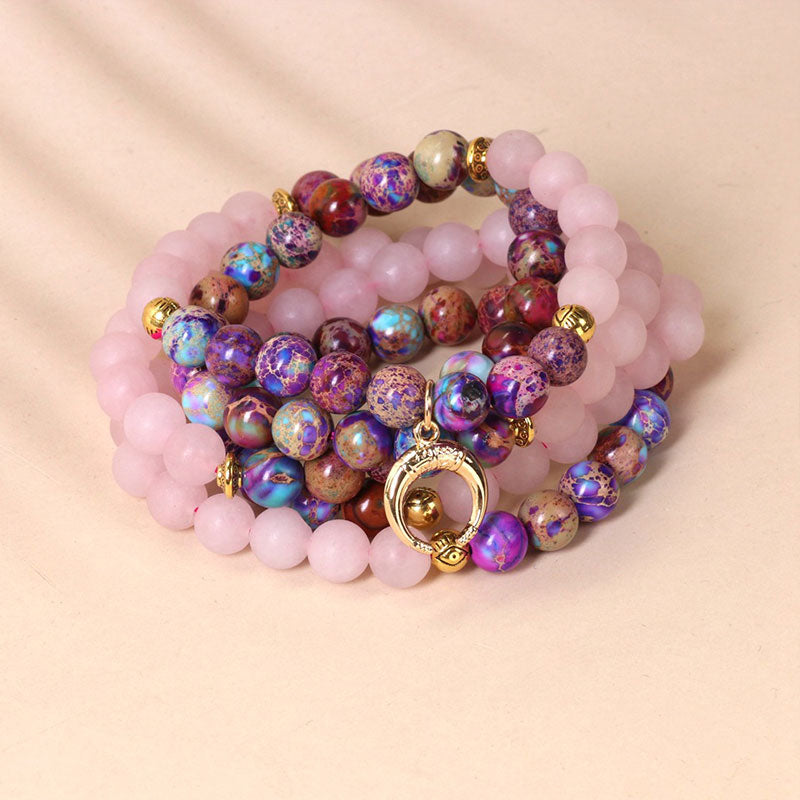 Stack of colorful beaded bracelets with a gold clasp on a beige background