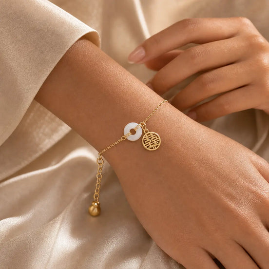 White Jade Double Happiness Bracelet worn on wrist with gold chain and two charms