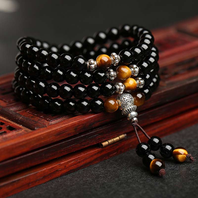 Black and orange beaded bracelet with tassel on a wooden surface