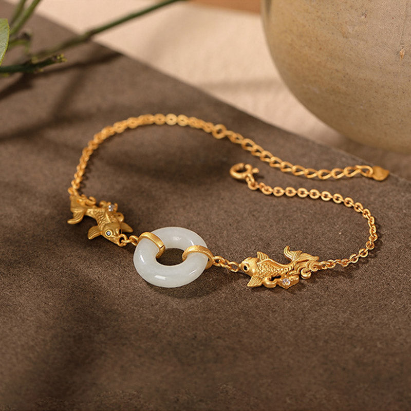 Gold bracelet with a jade charm on a brown surface