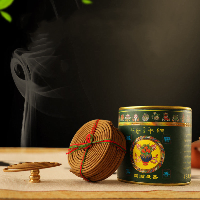Incense stick bundle and decorative tin on a table with smoke in the background