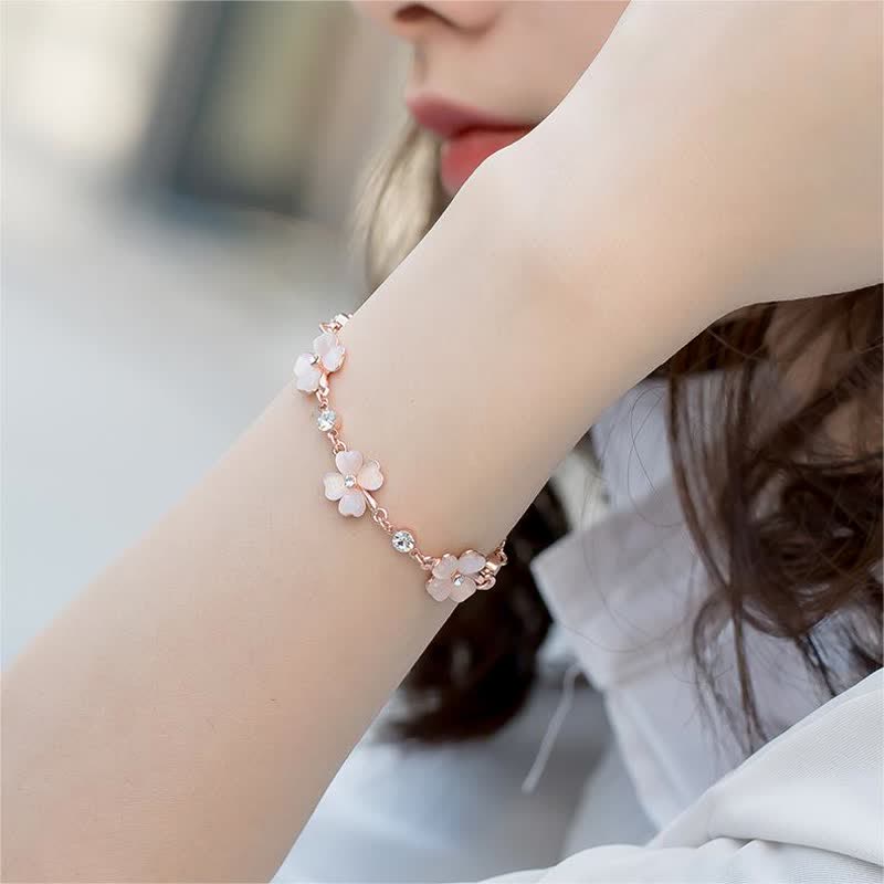 Crafted with rose gold-plated chain featuring three cherry blossom pink cat's eye clover flowers, each accented with sparkling crystal centers and star-shaped links, this bracelet exudes soft romance and symbolizes luck, hope, and love—perfect for gifting or personal wear.