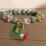 Jade Fu Charm Bracelet displayed on a wood tray with green and gold tones – TheFuMaster