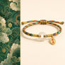 Colorful braided bracelet with a gold charm on a beige background