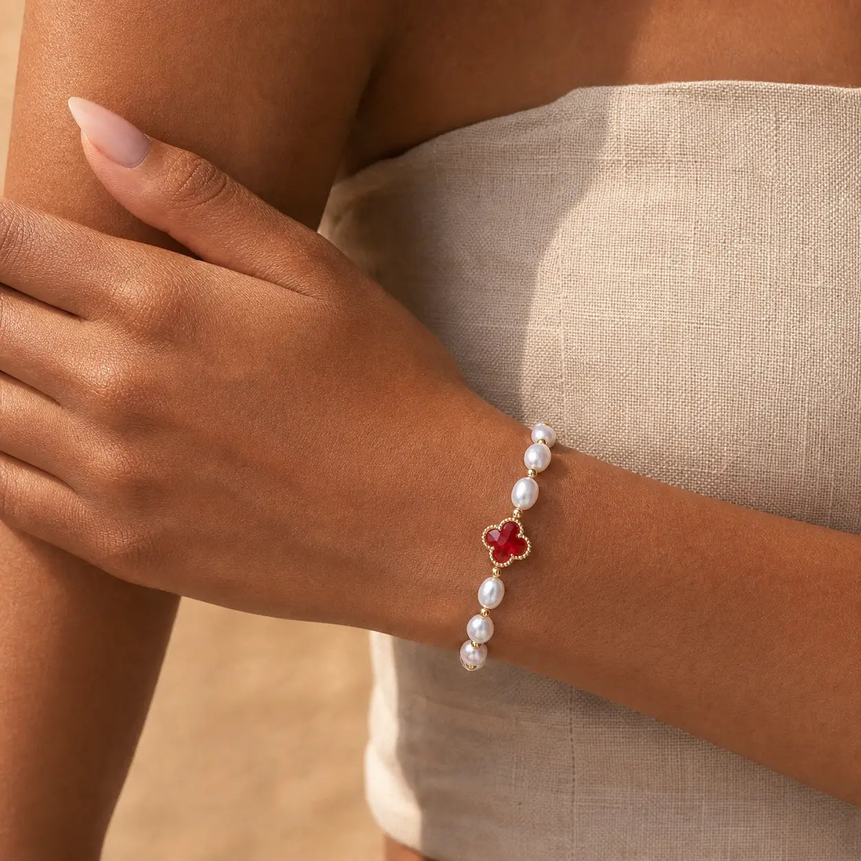 Luminous Synchronicity Clover Bracelet worn on hand with pearl beads and red clover charm