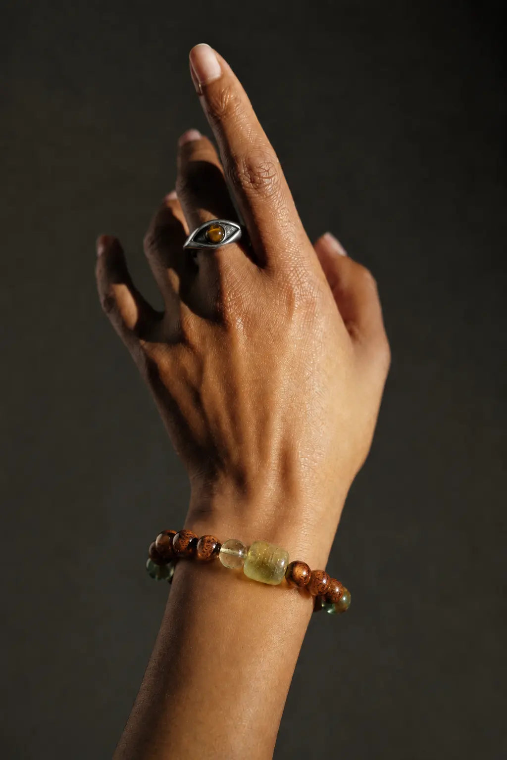 Hand wearing a gemstone bracelet and silver ring