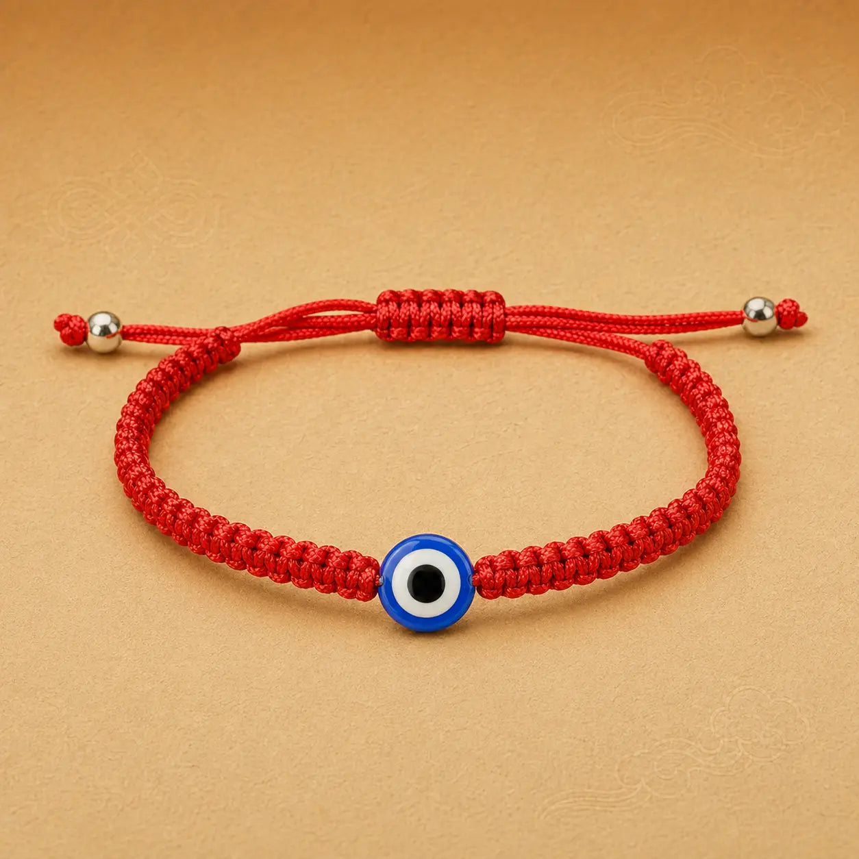 Red bracelet with a blue evil eye charm on a beige background