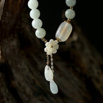Close-up detail of TheFuMaster Serene Blossom White Jade Bracelet with floral charm and jade drops.
