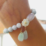 Hand view of TheFuMaster Serene Blossom White Jade Bracelet showing balance of jade beads and blossom charm.

