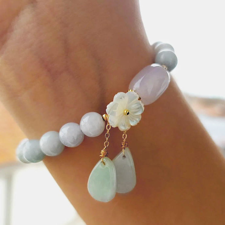 Hand view of TheFuMaster Serene Blossom White Jade Bracelet showing balance of jade beads and blossom charm.

