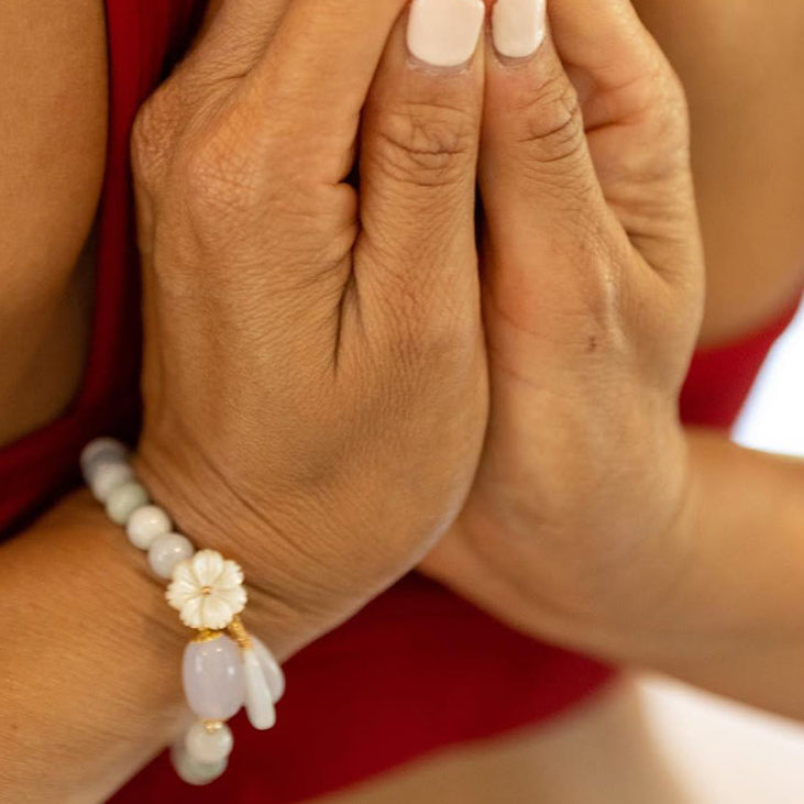 Lifestyle photo of Serene Blossom White Jade Bracelet worn during meditation or prayer.

