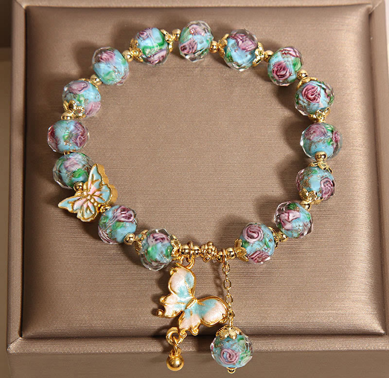 Bracelet with floral beads and butterfly charms on a brown box background