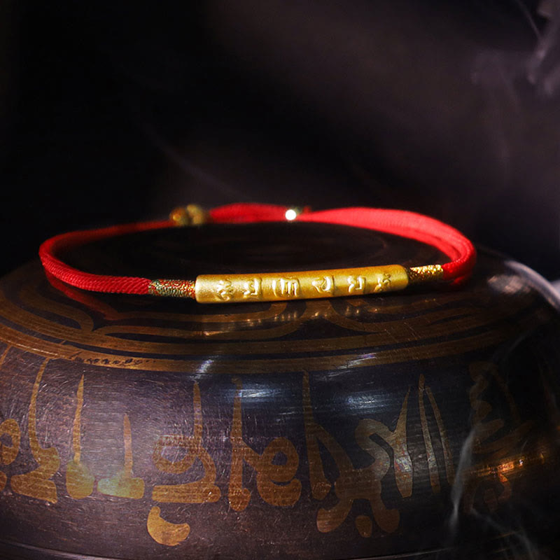 Gilded silver Tibetan mantra bracelet displayed on traditional setting with warm light