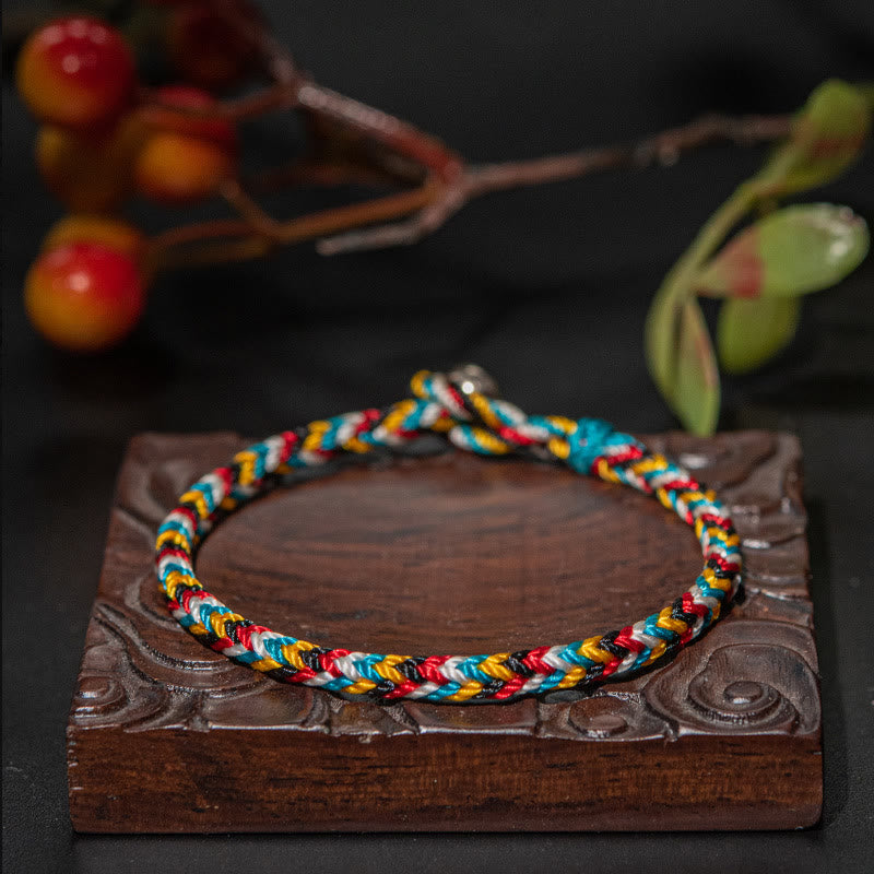 Vibrant Harmony Five-Color Protection Bracelet by TheFuMaster on carved wooden base, showcasing vivid Tibetan-style threads.
