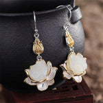 Close-up view of White Jade Lotus Drop Earrings featuring gold-plated lotus bud detail and natural jade texture